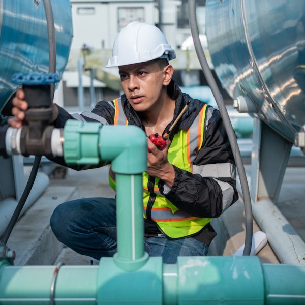 Focused industrial engineer using a calibration tool to check equipment at a manufacturing plant, ensuring operational efficiency.